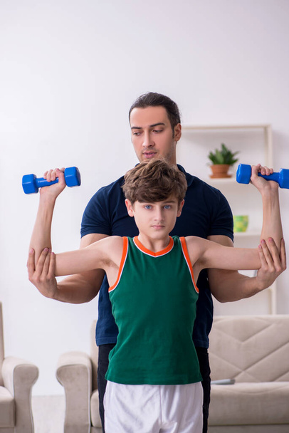 Padre e hijo haciendo ejercicios deportivos en interiores - Foto, Imagen