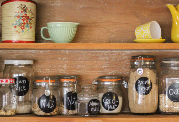 Деревянный антикварный кухонный шкаф с банками выпечки ингредиентов и ретро-посуда - Фото, изображение