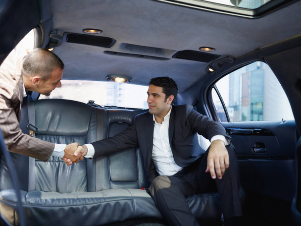 Imprenditori che si incontrano in limousine e stringono le mani - Foto, immagini