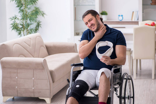 Młody ranny w nogę mężczyzna na wózku inwalidzkim cierpiący w domu - Zdjęcie, obraz