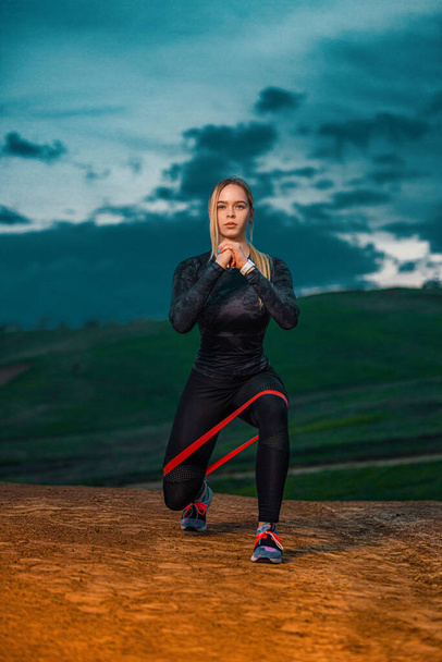 Workout with bands or expander outdoors. Individual sports recreation. Sporty and fit young woman athlete have a training on the sky background. Concept of a healthy lifestyle and sport. - Foto, Imagem