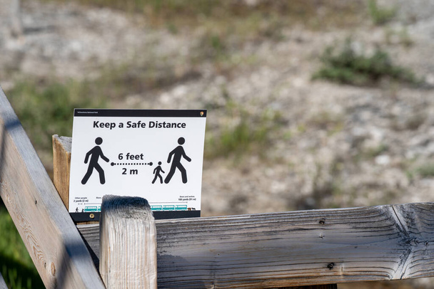 Вайомінг (США) - 2 липня 2020: Підпишіть на головній дорозі в Єллоустонському національному парку, нагадуючи відвідувачам, що під час пандемії COVID-19 безпечна відстань 6 футів одна від одної - Фото, зображення