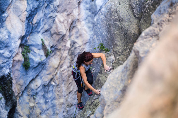 A woman is climbing in Turkey, Turkish woman climbs the rock, Extreme hobby, Overcoming a difficult climbing route, Overcoming the fear of heights, Climbing effort. - Photo, Image