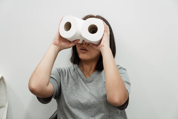 Funny asian woman making eyeglasses with tissue paper rolls. Funny girl have fun with tissue paper rolls. - Zdjęcie, obraz