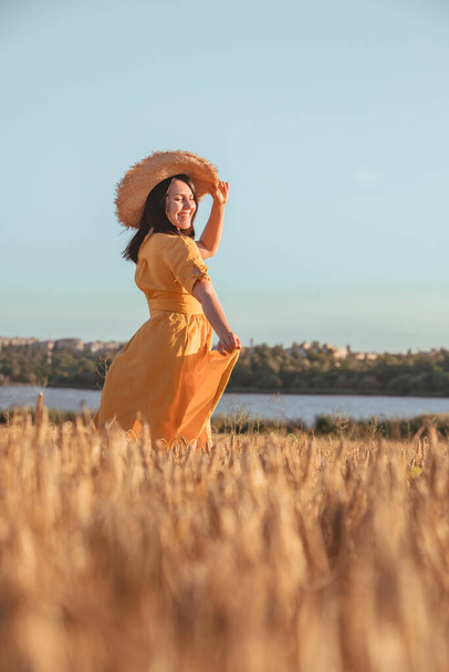 mujer en vestido amarillo caminando por el campo de trigo. hora de verano - Foto, imagen