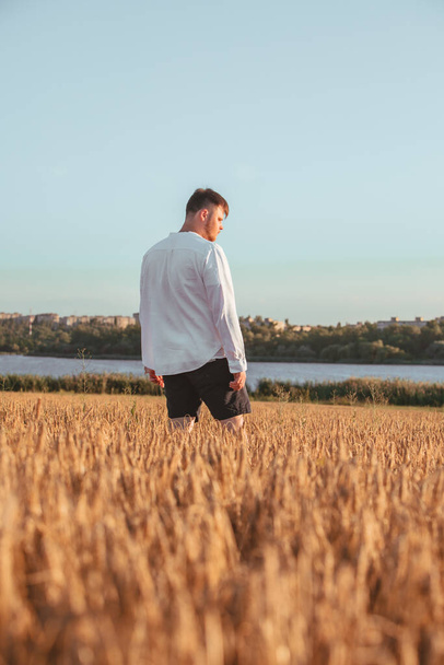людина ходить на заході сонця в пшеничному полі. озеро на фоні
 - Фото, зображення