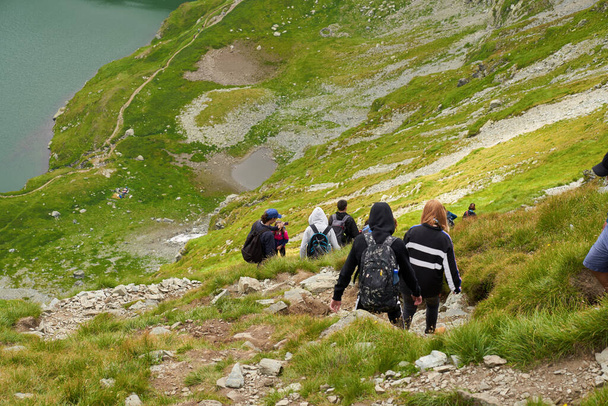 ROMANIA, FAGARAS MOUNTAINS  - 2ND AUGUST, 2020: Group of people with backpacks hiking on a trail to Capra lake - Zdjęcie, obraz