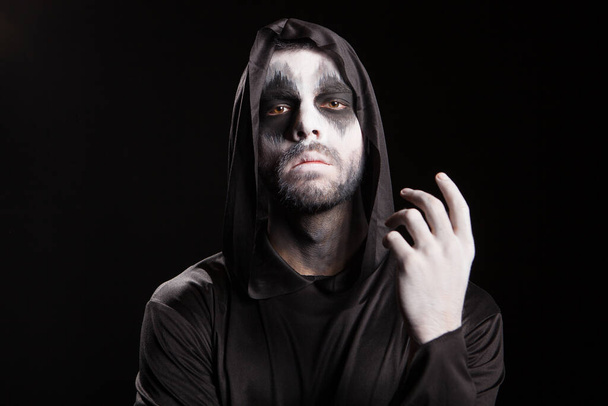 Spooky man dressed up like a grim reaper over black background - Photo, Image