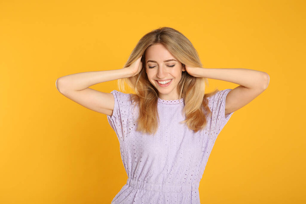 Portrait of beautiful young woman with blonde hair on yellow background - Φωτογραφία, εικόνα