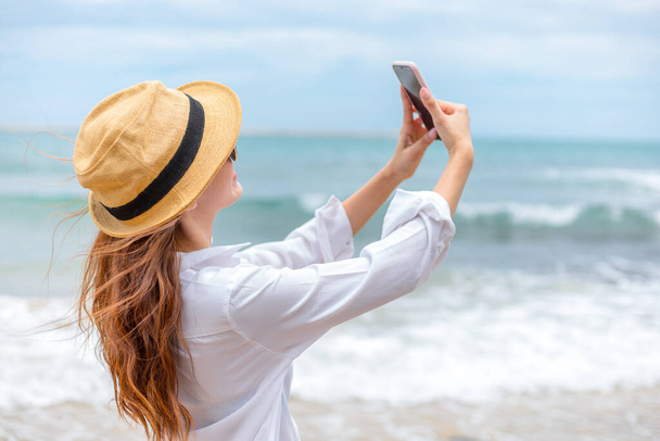 Happy young women wearing  sun glasses use mobile phones to take pictures on the beach While traveling - Foto, Imagem