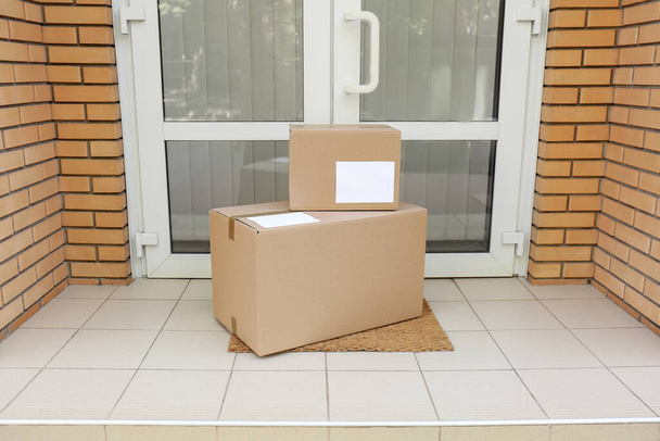 Delivered parcels on door mat near entrance - Фото, изображение