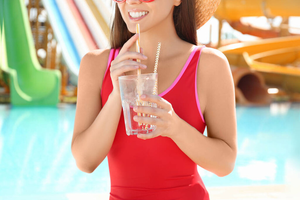 Woman with glass of refreshing drink in water park, closeup - Foto, imagen