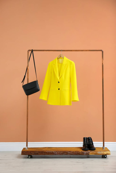 Rack with stylish women's clothes and boots near color wall - Fotoğraf, Görsel
