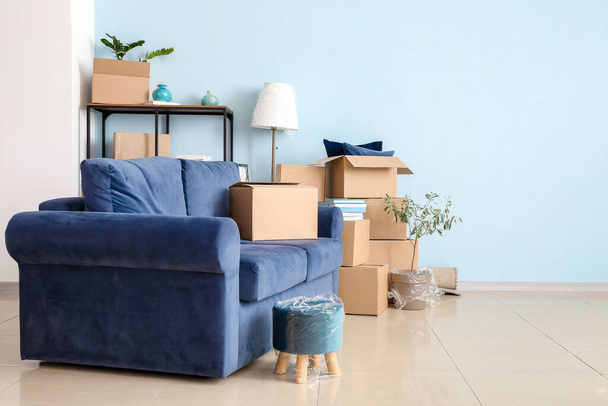 Картонные коробки с вещами и диваном в новой квартире в день переезда - Фото, изображение