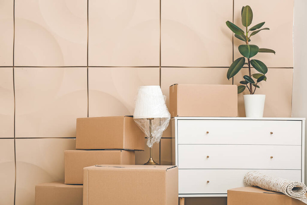 Boîtes en carton avec effets personnels et commode dans un nouvel appartement le jour du déménagement - Photo, image
