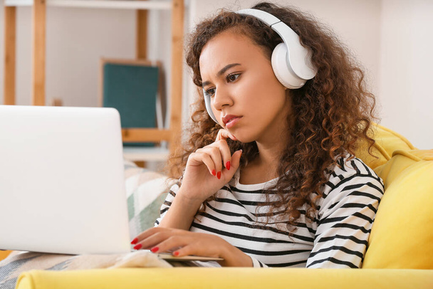 Afroamerykanka ze słuchawkami pracująca na laptopie w domu - Zdjęcie, obraz