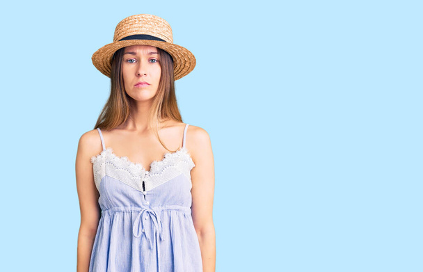 顔に深刻な表情で夏の帽子をかぶって美しいブルネットの若い女性。カメラを見ているだけで.  - 写真・画像