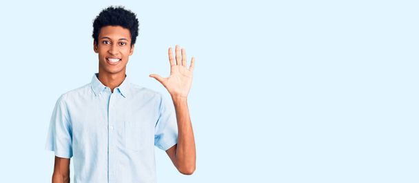 Mladý africký Američan nosí ležérní oblečení ukazující a ukazující nahoru s prsty číslo pět a zároveň se usmívá sebevědomě a šťastně.  - Fotografie, Obrázek