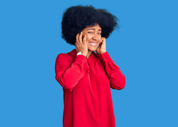 Молода афроамериканська дівчина, одягнена в повсякденний одяг, закриває вуха пальцями з роздратованим виразом для гучної музики. концепція глухих.  - Фото, зображення
