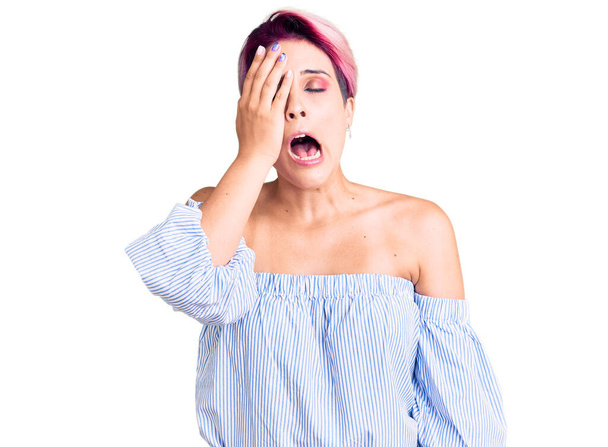 Young beautiful woman with pink hair wearing casual clothes yawning tired covering half face, eye and mouth with hand. face hurts in pain.  - Photo, Image
