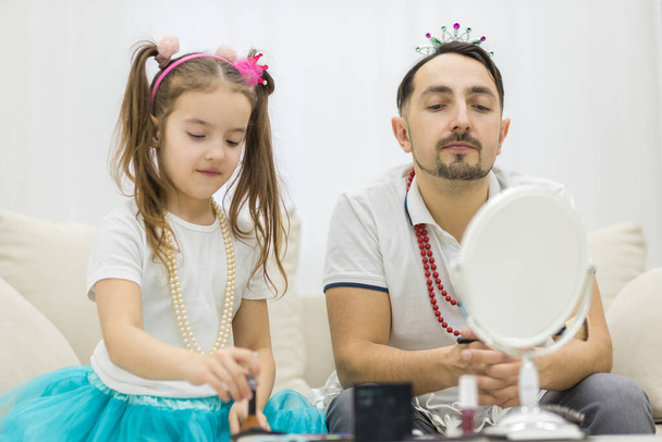 Cute little girl making makeup to her dad. - Valokuva, kuva