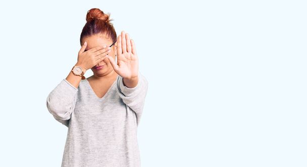 Молодая латинская женщина в повседневной одежде закрывает глаза руками и делает стоп-жест с грустным и испуганным выражением лица. смущенная и негативная концепция.  - Фото, изображение