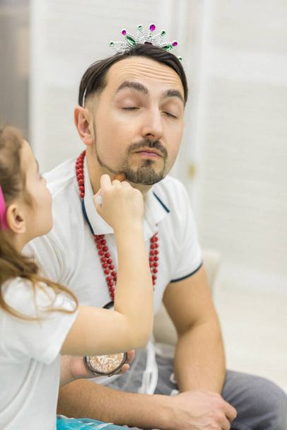 Cute little girl making makeup to her dad. - Foto, Bild