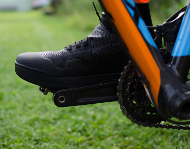 Київ, Україна. 04 August 20.Close image of mens black sneaker, cyvelist верхова їзда на гірському велосипеді зеленою травою. - Фото, зображення