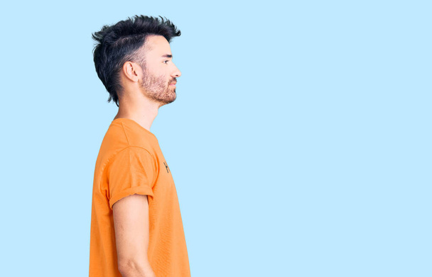 Homem hispânico jovem vestindo t-shirt com mensagem palavra felicidade olhando para o lado, relaxar pose perfil com rosto natural e sorriso confiante.  - Foto, Imagem