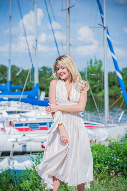 Nice blonde lady in yacht club. Woman in flying silk white dress at outdoor, relax time - Foto, Bild