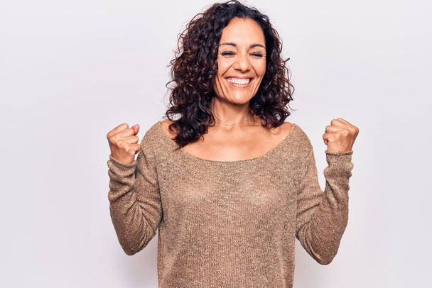 Middle age beautiful woman wearing casual sweater celebrating surprised and amazed for success with arms raised and eyes closed  - Foto, imagen