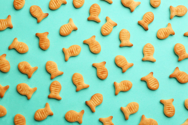 Delicious goldfish crackers on turquoise background, flat lay - Photo, image