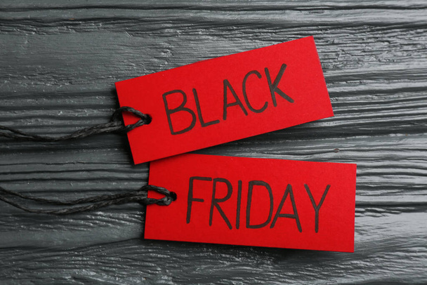 Red tags with words BLACK FRIDAY on dark wooden background, flat lay - Foto, Imagem