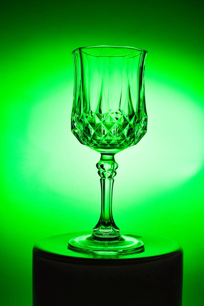 Wineglass on the light background. Fine cristal glassware concept. Vertical, toned in green - Photo, image