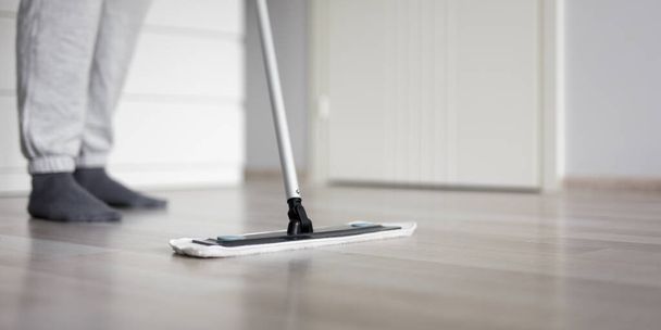 concepto de limpieza - hombre limpieza suelo de madera con fregona en la sala de estar moderna - Foto, Imagen
