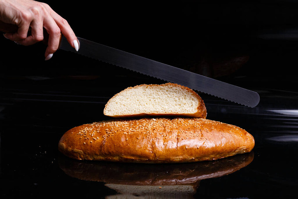 Zelfgebakken gebak. Knapperig wit brood gesneden met een mes. - Foto, afbeelding
