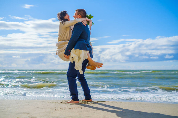 Happy bride and groom hugging on beach - Φωτογραφία, εικόνα