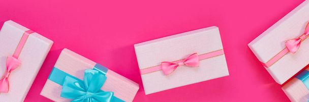 Banner from set of beautiful gift boxes with blue bows on pink background. Holiday sale. Copy space for your text. Flat lay, top view, copy space concept - Photo, image