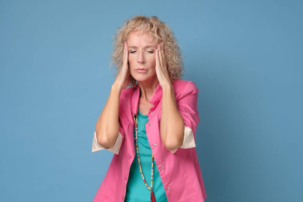 Caucásica mujer mayor con un dolor de cabeza frotando sus sienes - Foto, imagen