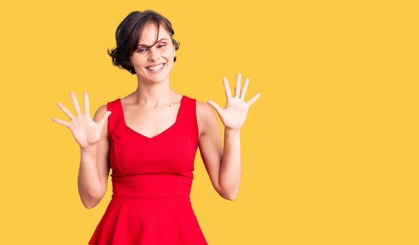 Красивая молодая женщина с короткими волосами носить случайный стиль с рукавами рубашку показывая и указывая пальцами номер десять, улыбаясь уверенно и счастливо.  - Фото, изображение
