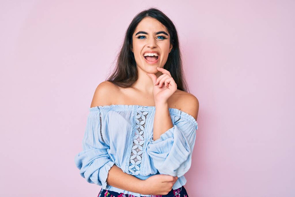Brunette teenager girl wearing casual clothes smiling looking confident at the camera with crossed arms and hand on chin. thinking positive.  - Photo, Image