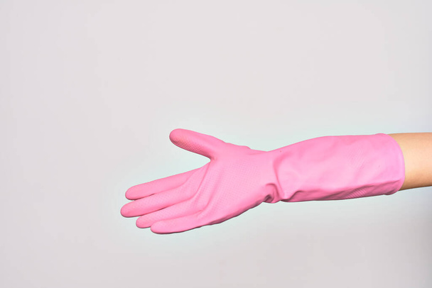 Main de jeune femme caucasienne portant un gant de nettoyage rose faisant me donner signe. Affichage ouvert la paume vide sur fond blanc isolé - Photo, image