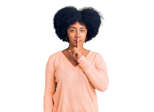A fiatal afro-amerikai lány alkalmi ruhát visel, és azt kéri, hogy maradjon csendben, ujjal a száján. csend és titkos koncepció.  - Fotó, kép