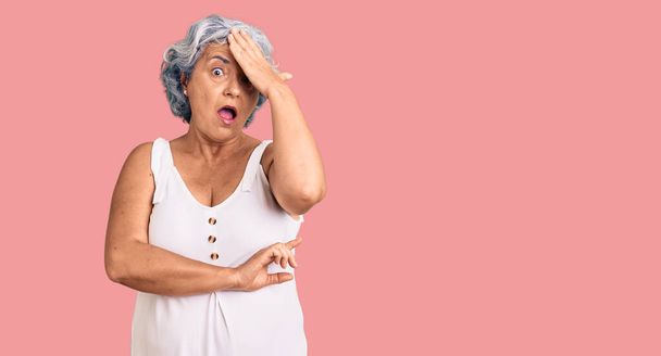 Oudere vrouw met grijs haar draagt casual kleding verrast met de hand op het hoofd voor fout, herinner fout. vergeten, slecht geheugen concept.  - Foto, afbeelding