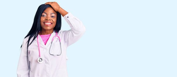 Fiatal afro-amerikai nő visel orvos sztetoszkóp mosolygós magabiztos megható haj kéz fel gesztus, pózol vonzó és divatos  - Fotó, kép
