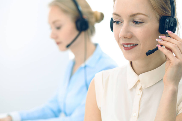 Bright and sunny call center. Group of blonde women in headset at work. Office and business concept. - Foto, Bild