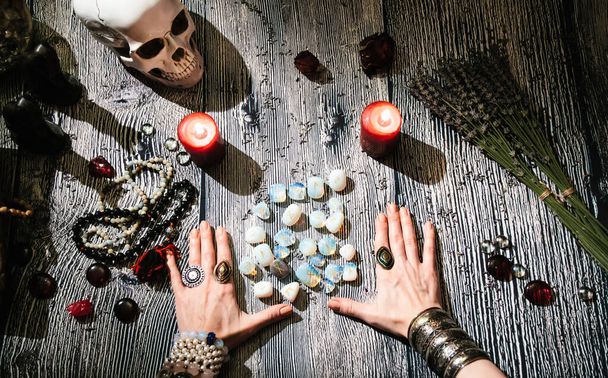 Věštcovy ruce s kamennými runami, pohled shora. Předpověď budoucnosti. Mystický interiér. Okultní symboly, růžence, svíčky, suchá levandule - Fotografie, Obrázek