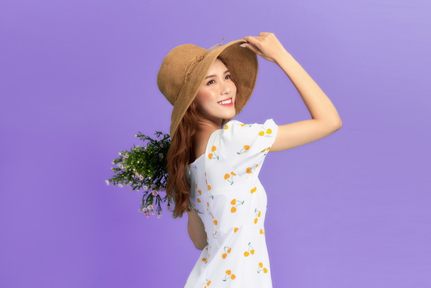 Girl in hat and flower dress poses with bouquet. - Foto, Imagen