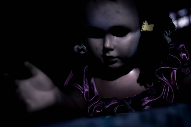 怖いと妹の人形は暗闇から出てきて、ベッドに登る。巨大な黒い目と表情のない顔。ベッドルームでの恐怖や不穏な概念. - 写真・画像