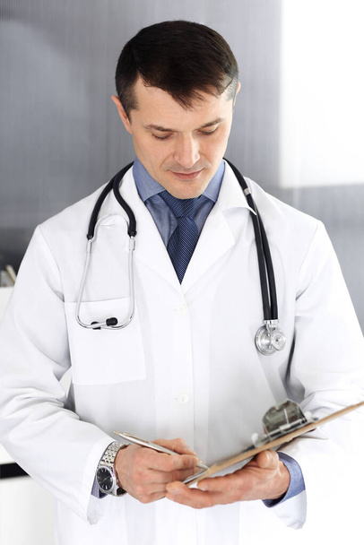 Doctor man using clipboard for filling up medication history records. Perfect medical service in clinic. Physician at work in hospital. Medicine and healthcare concepts - Foto, Imagem